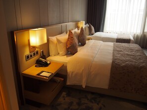 A hotel room with a large bed, a bedside table with a lamp, a phone, and a notepad. - WOJO Hotel (Shaoxing)