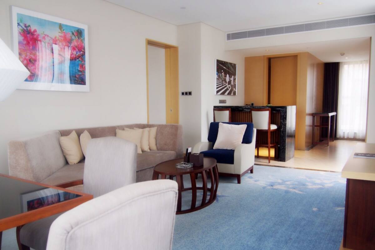 Una sala de estar moderna con un sofá, sillones, una mesa de centro y un comedor con una mesa y sillas.