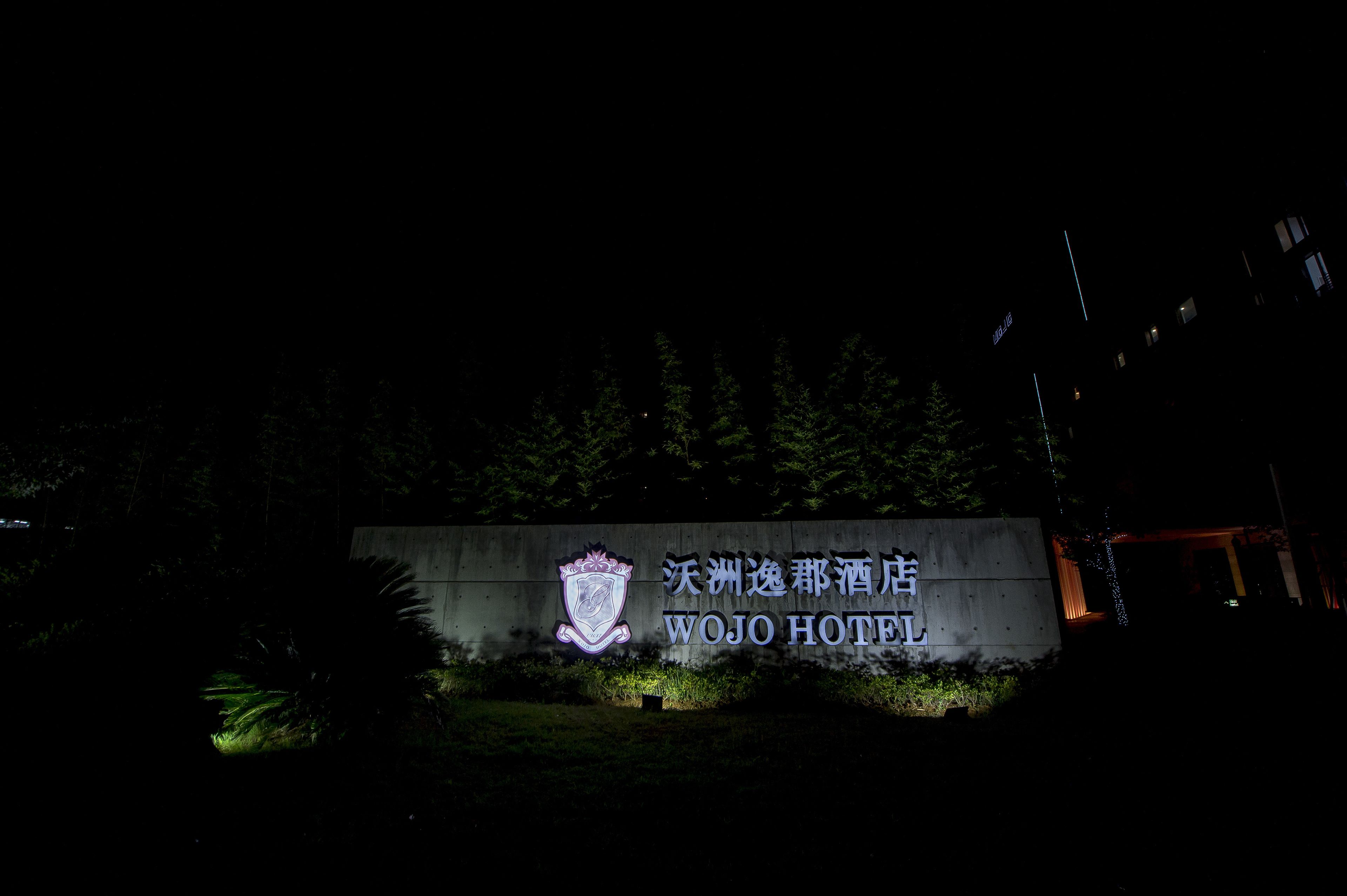 Une enseigne de l’hôtel Wojo, illuminée par un éclairage artificiel, la nuit.