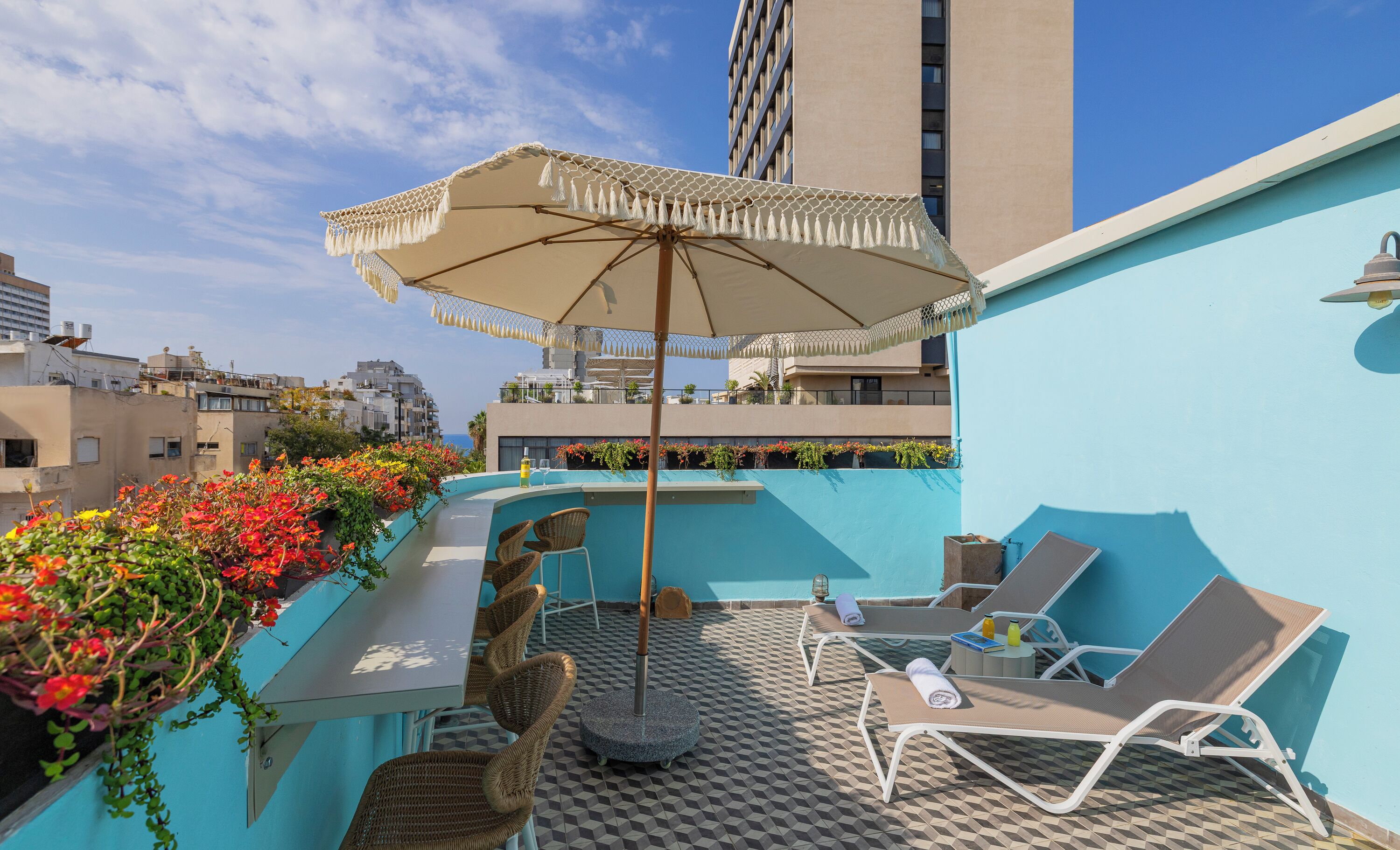 Una terraza en la azotea con piscina, sillas de descanso y una sombrilla.