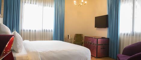 Habitación de hotel con cama, escritorio, silla, televisor y teléfono.