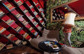 Un rincón acogedor para leer con un sofá, una mesita con un libro y una taza, y una estantería llena de libros.