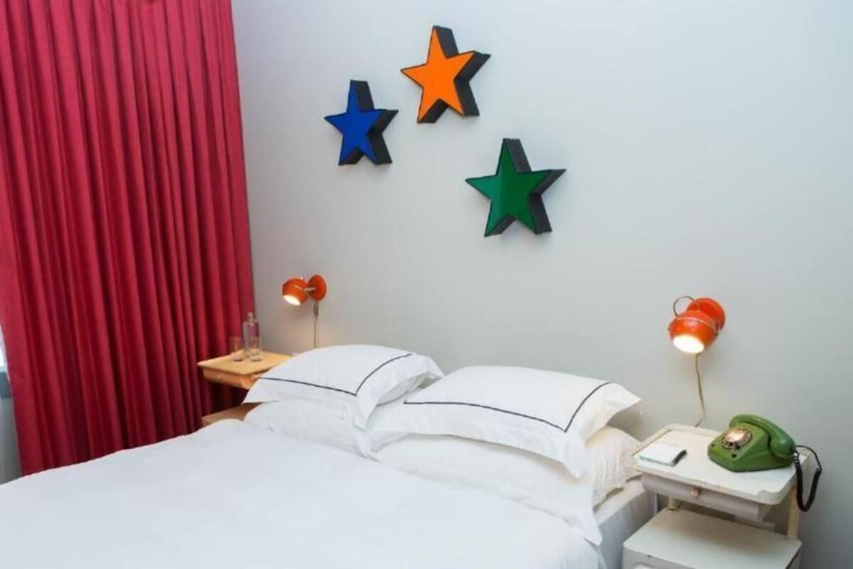 A hotel room with a bed, red curtains, and three wall-mounted stars.