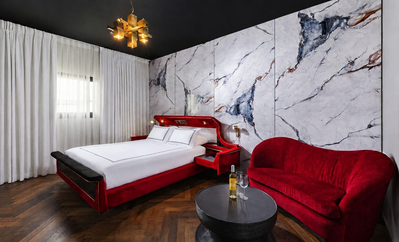 Ein modernes Schlafzimmer mit einem Bett, einem rot gepolsterten Sessel und einer Wand mit Marmormuster.