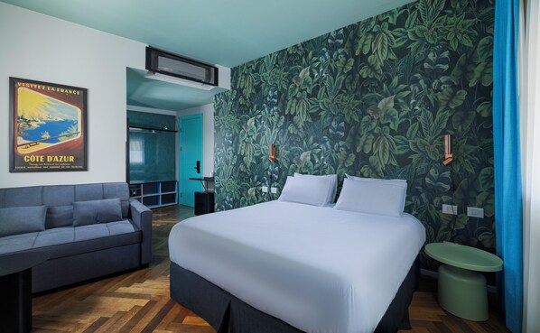 Un dormitorio con una cama, un sofá, una mesita, un cubo de basura y un cartel en la pared.