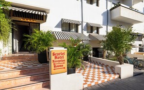 Entrada de hotel con un cartel que indica recepción y habitaciones.