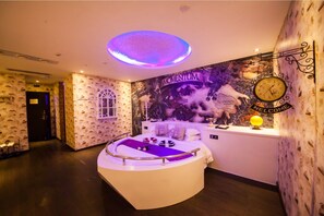 Une chambre avec un lit rond, une horloge murale et une fresque représentant des images liées aux Jeux olympiques.