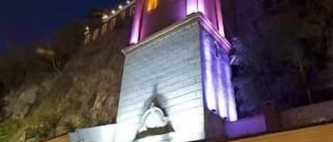 Un hotel con una imponente torre, una entrada espaciosa y un área ajardinada con plantas.