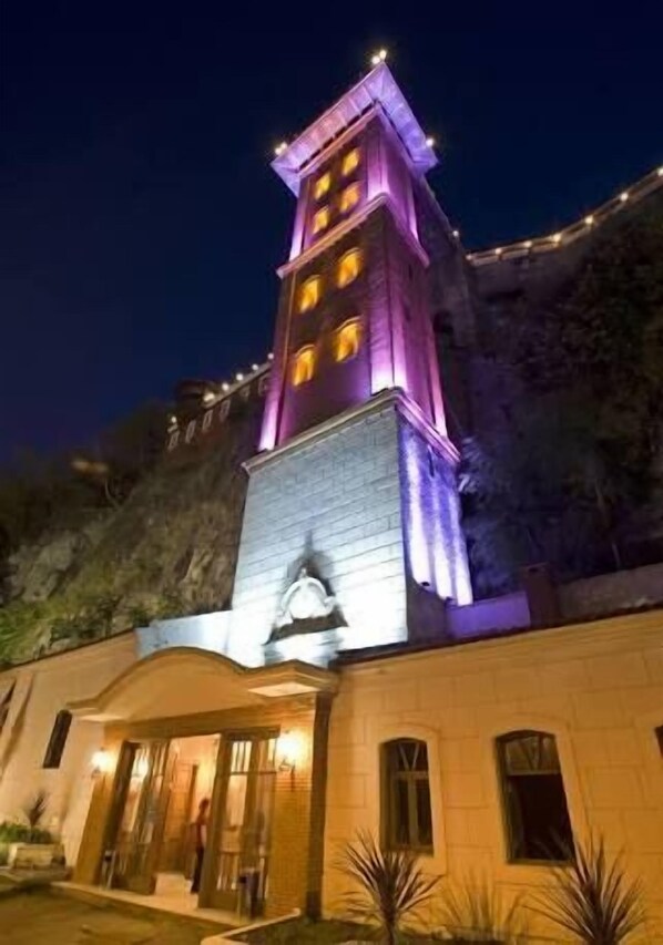 Un hotel con una imponente torre, una entrada espaciosa y un área ajardinada con plantas.