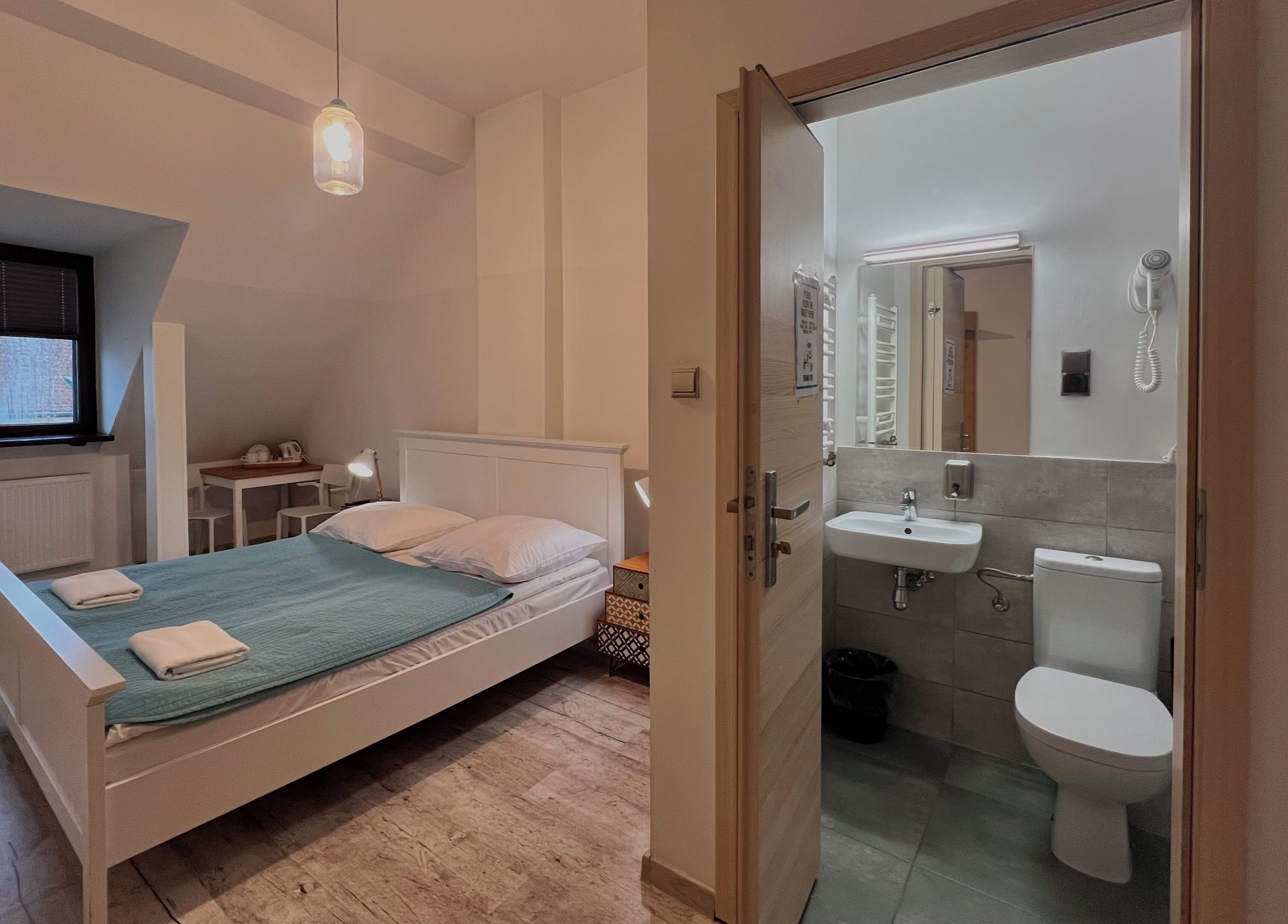 A bedroom with a bed, bedside table, lamp, and a window.