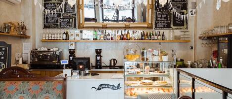 A café with a bar area, patterned seating, and a tiled floor.