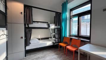 Ein kleines Zimmer mit Etagenbetten, einem Tisch und Stühlen.