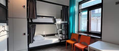 A compact room with bunk beds, a small table, and chairs.