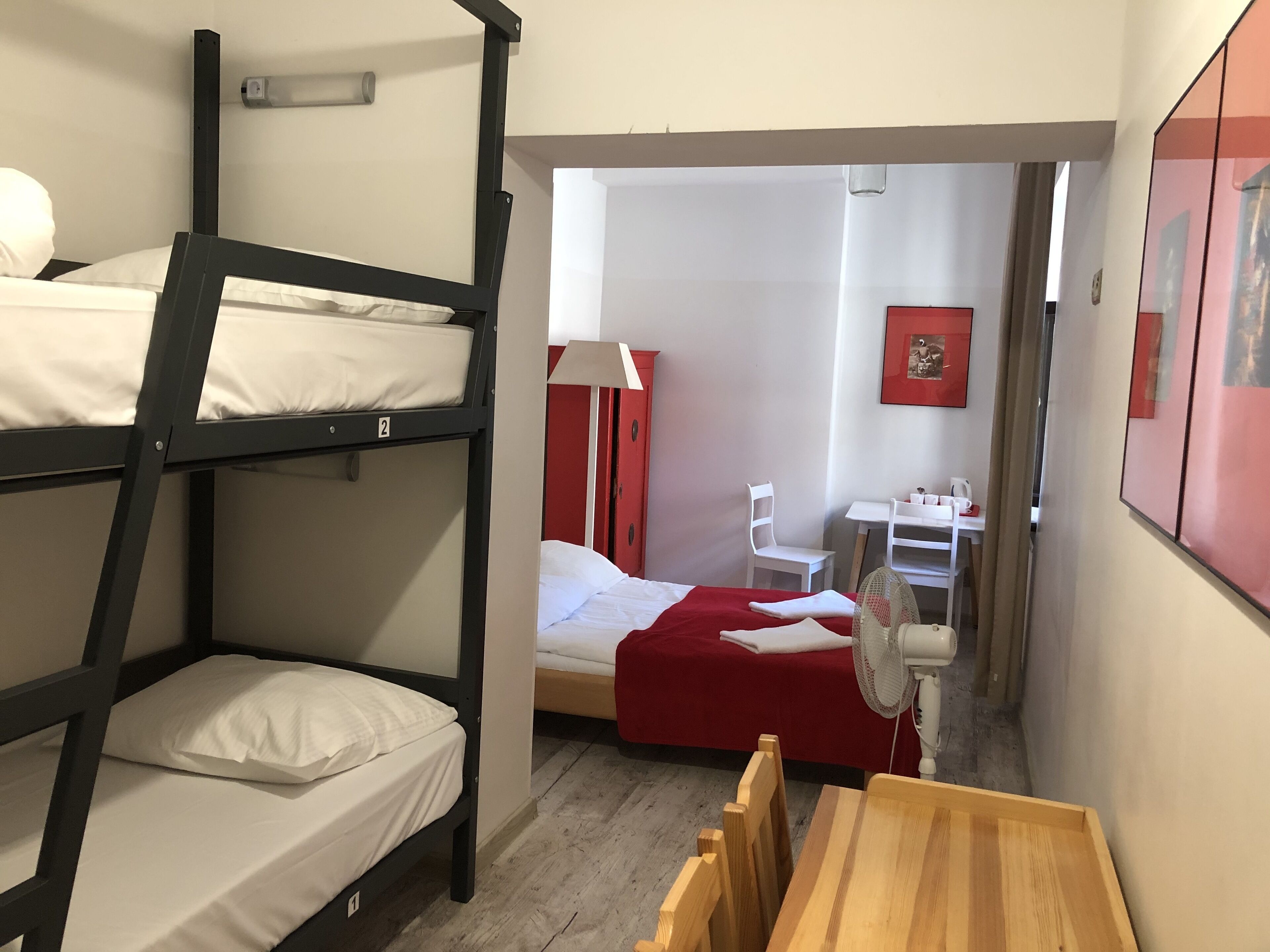 A bunk bed room with a desk, chair, and fan.