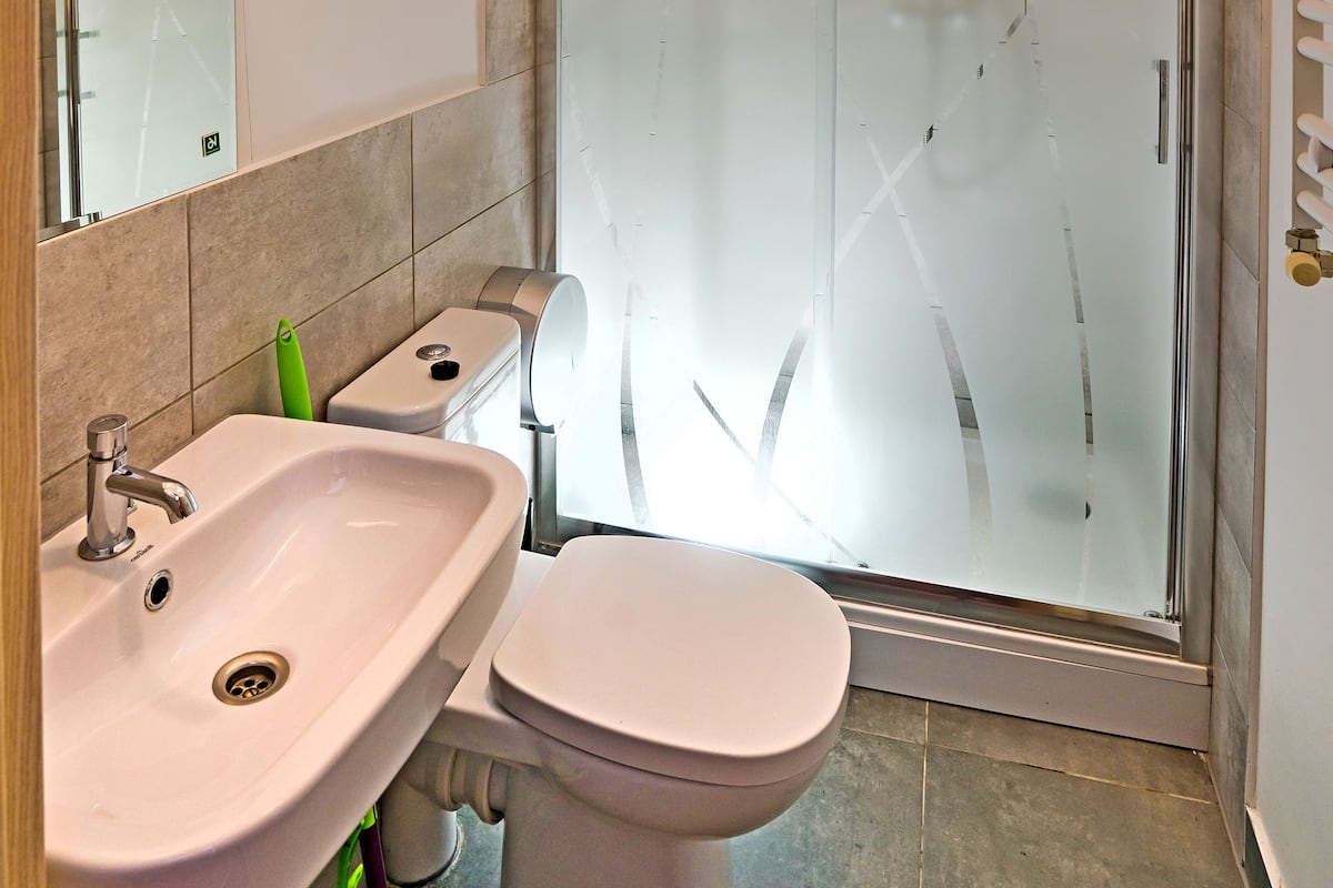 A bathroom with a sink, toilet, and glass shower enclosure.