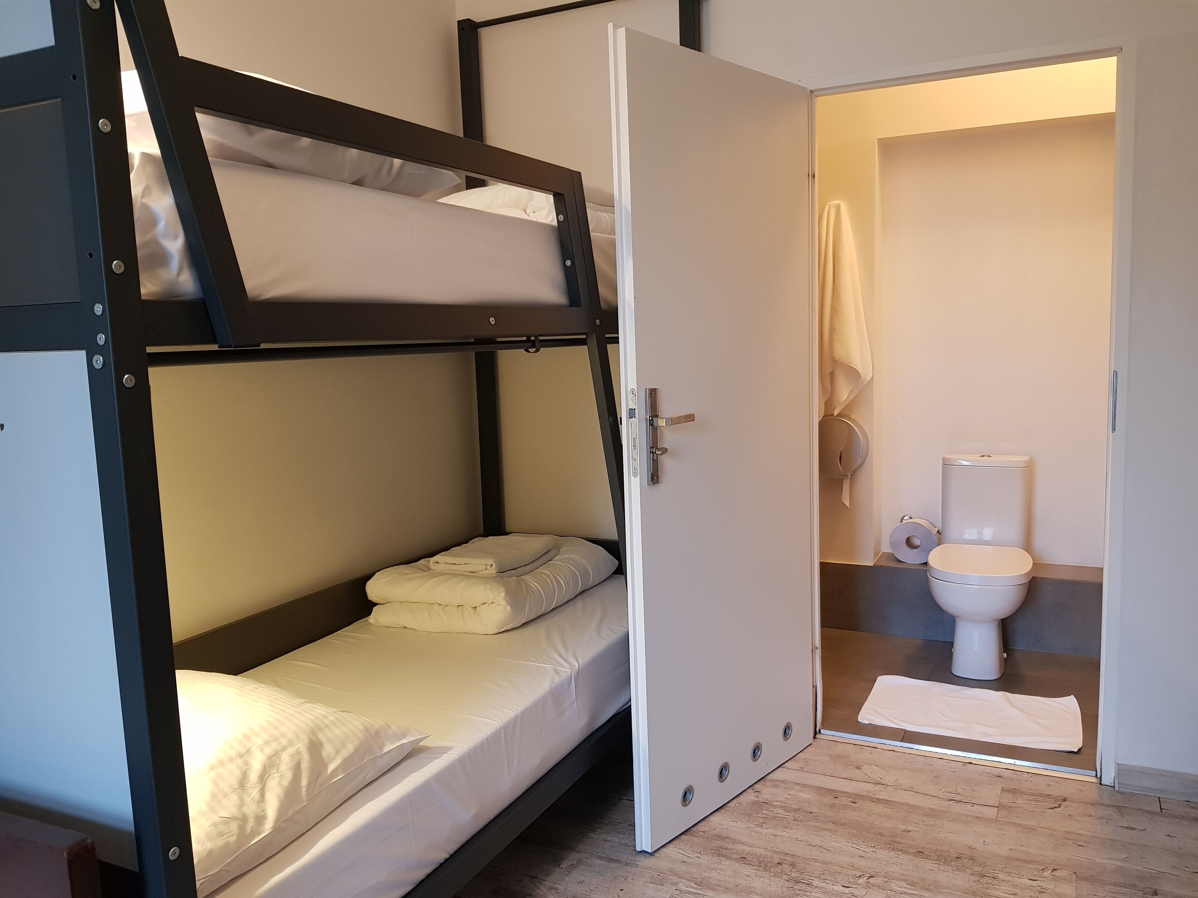 A bunk bed room with a white door leading to a bathroom.