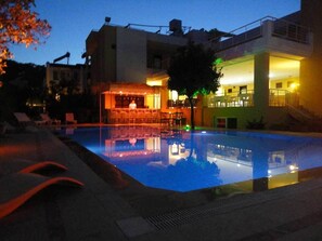 Una piscina al aire libre, sombrillas, sillones reclinables de piscina