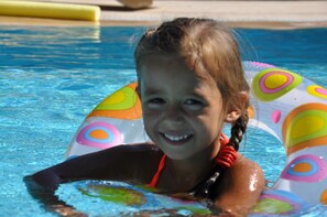 Una piscina al aire libre, sombrillas, sillones reclinables de piscina
