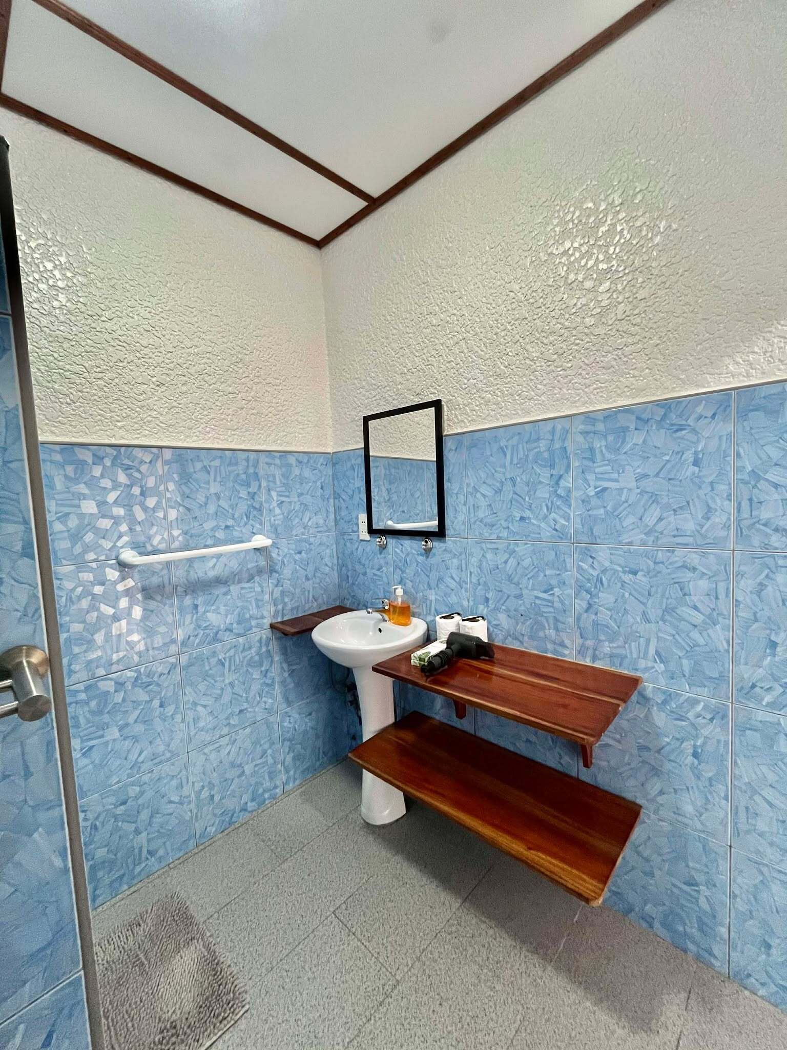 Un bagno con lavandino, specchio e mensola in legno.