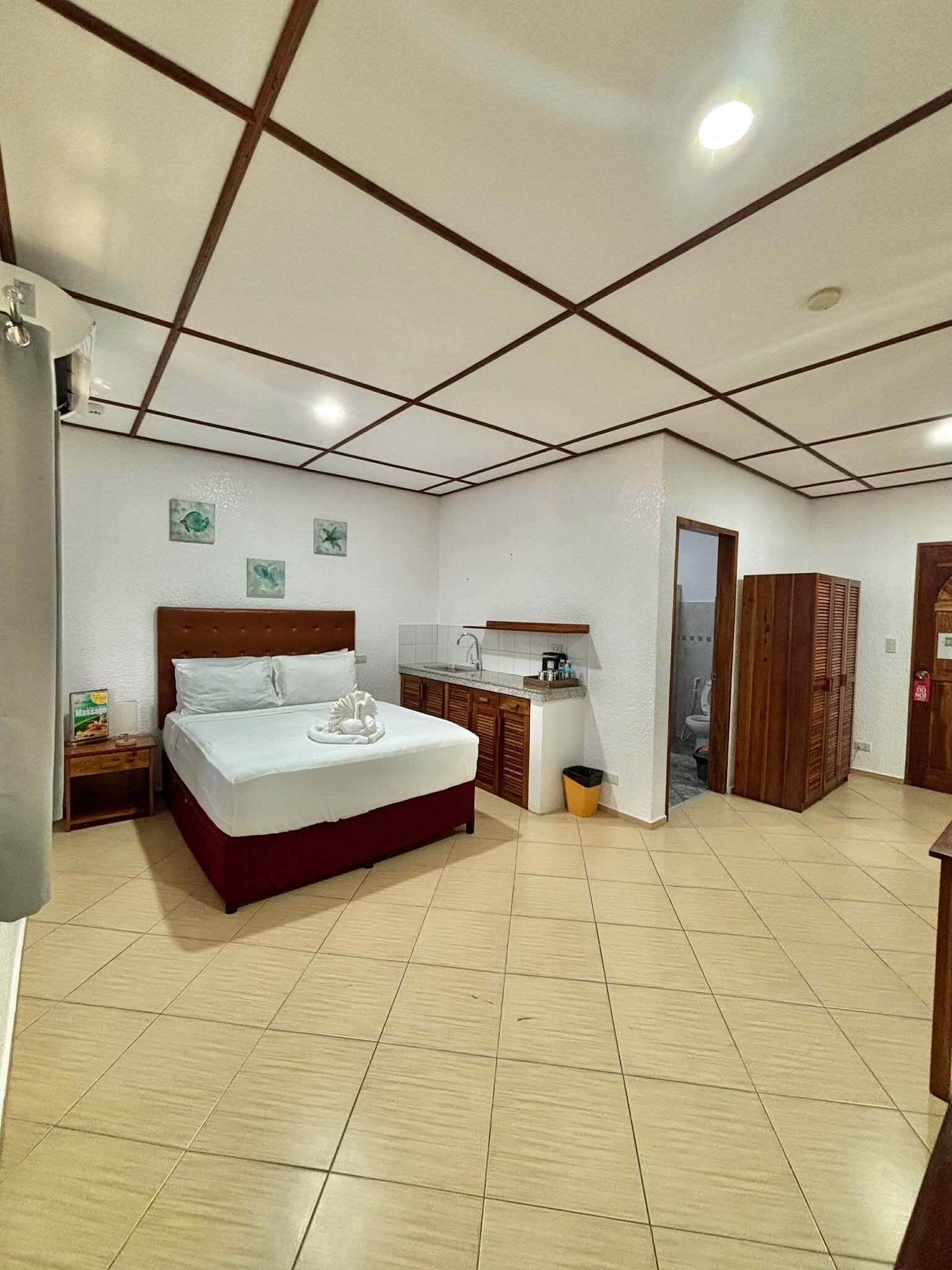 A hotel room with a bed, a small desk, a sink, and a wardrobe.