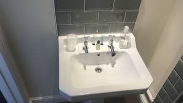 Un lavabo de salle de bain avec un bac blanc, un miroir et une fenêtre au-dessus.