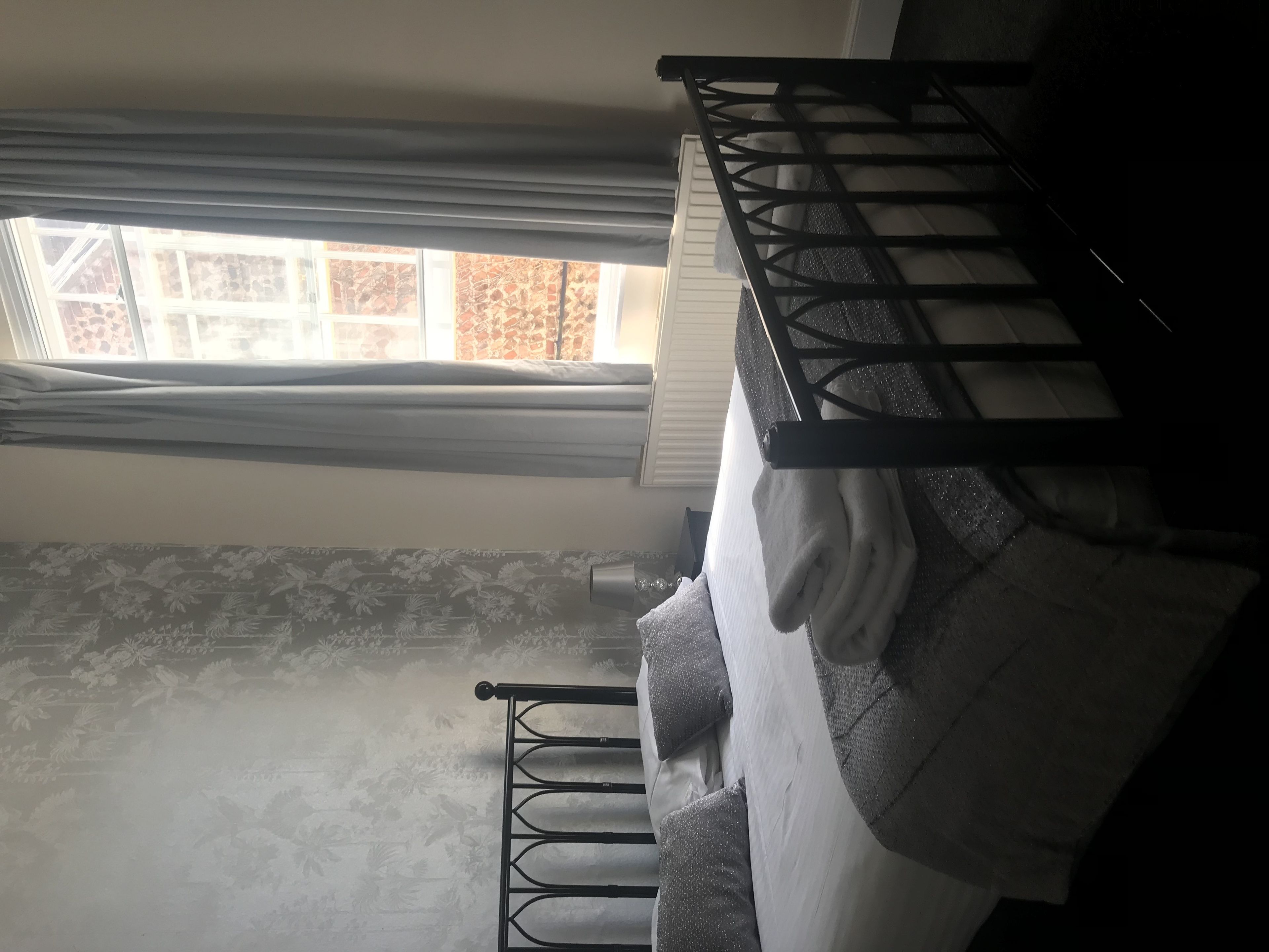 A bunk bed with a window above, a patterned wall, and a metal ladder.