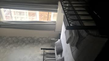 A bunk bed with a window above, a patterned wall, and a metal ladder.