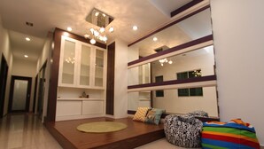 A modern living room with a wooden platform, a sofa, a colorful bean bag, and a large mirror reflecting the room.