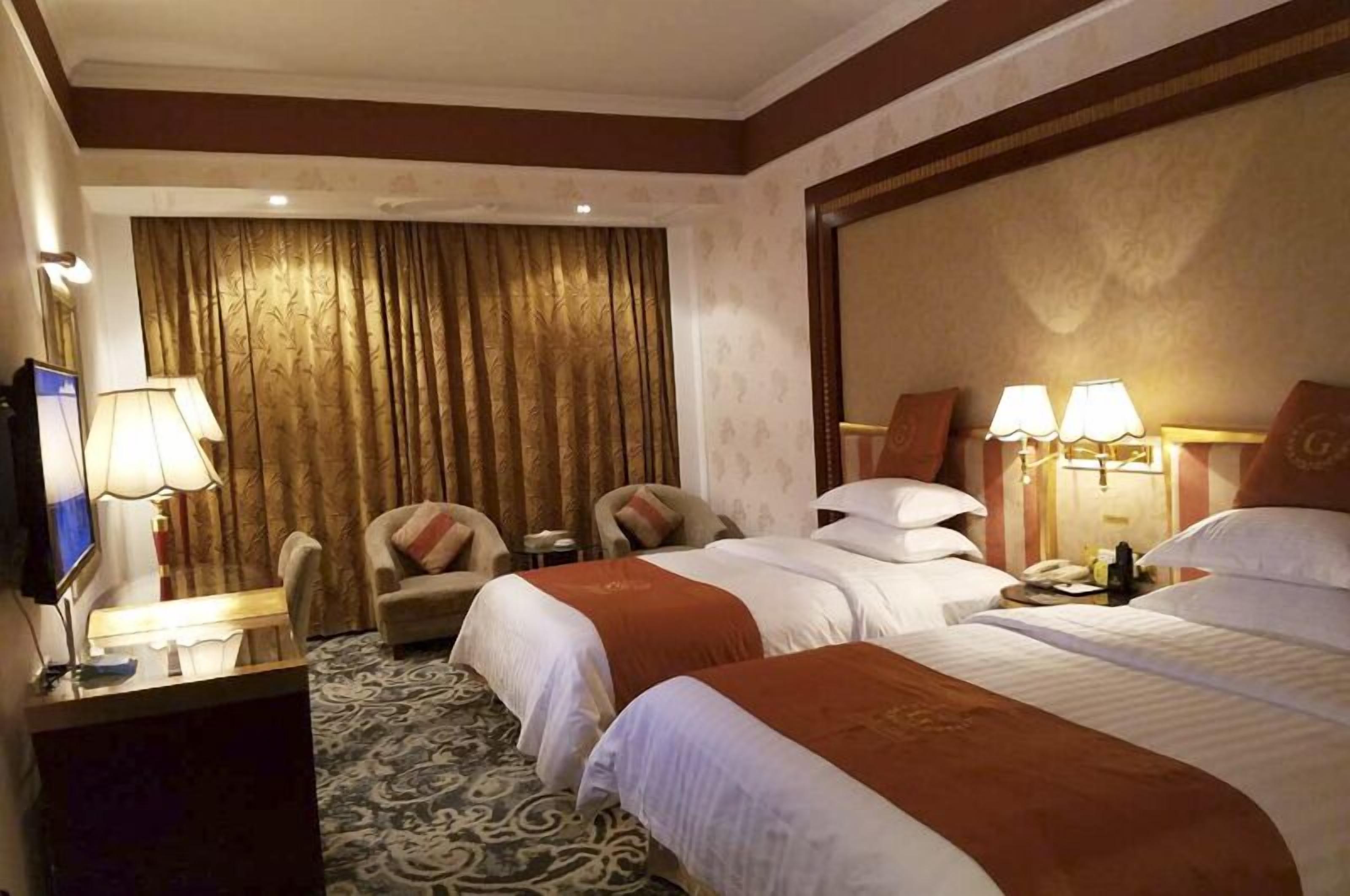 Una habitación de hotel con dos camas, un escritorio con lámpara, televisión y una silla.