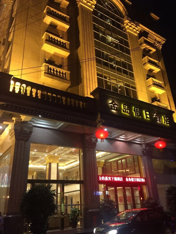 A hotel entrance with traditional architectural elements, including columns and a sign in a foreign script.