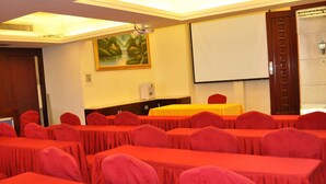 A conference room with rows of tables and chairs, a projector screen, and a painting on the wall. - Golden Island Holiday Hotel Foshan (Foshan)