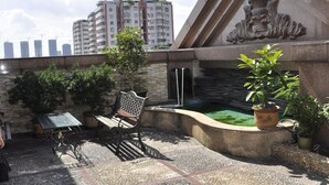 A rooftop patio with a stone wall, a bench, a table, and potted plants. - Golden Island Holiday Hotel Foshan (Foshan)
