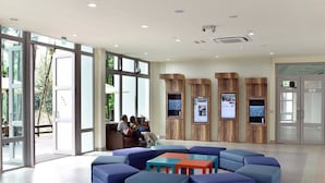 Een moderne lobby met grote ramen, blauwe zitplaatsen en houten accentmuren.