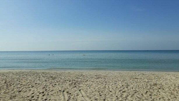 Una amplia playa de arena con agua tranquila y cielo despejado.