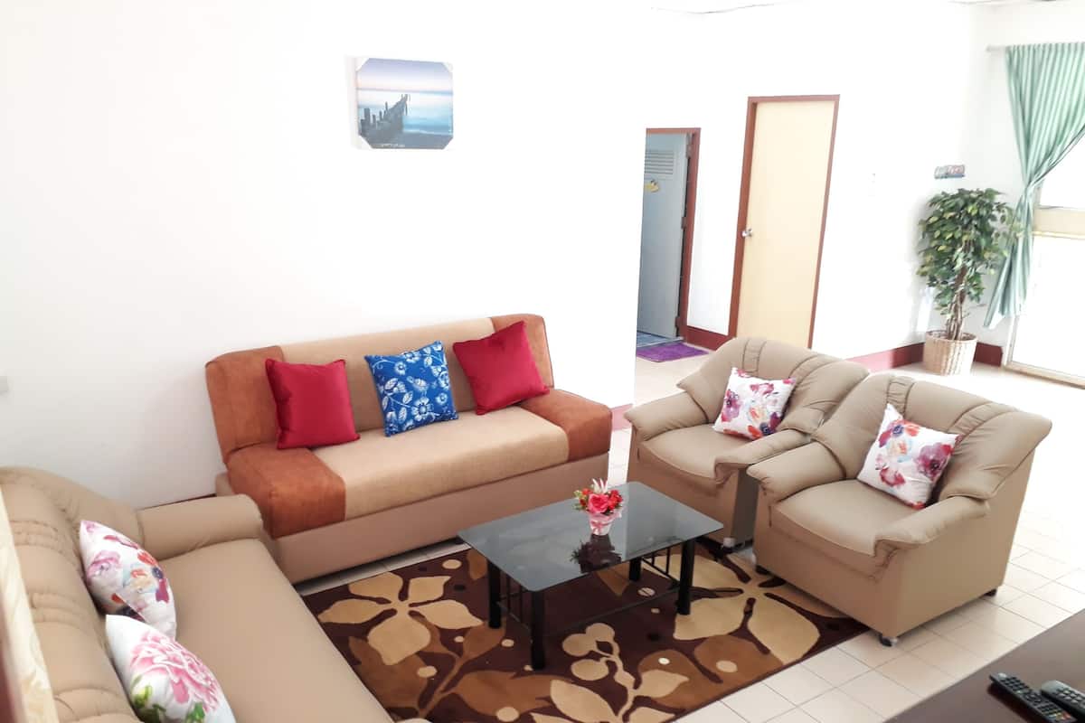 Una sala de estar con sofá, sillones, una mesa de centro y televisor.