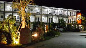 A multi-story hotel with balconies, a well-lit entrance, and a large rock in the foreground. - Rayonghouse Resort (Rayong)