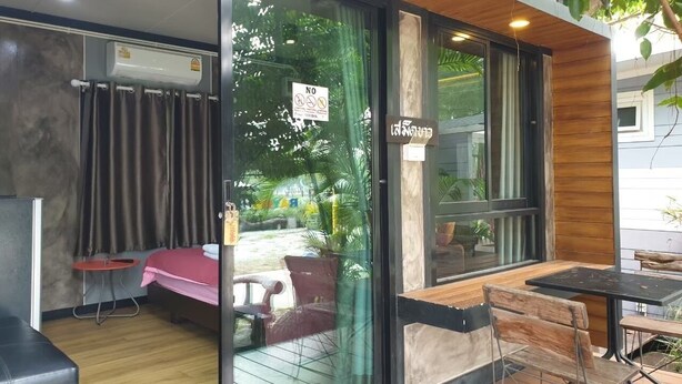 A modern interior with a dining area, a small seating area with a table and chairs, and a view of the outdoors through a glass door. - Rayonghouse Resort (Rayong)