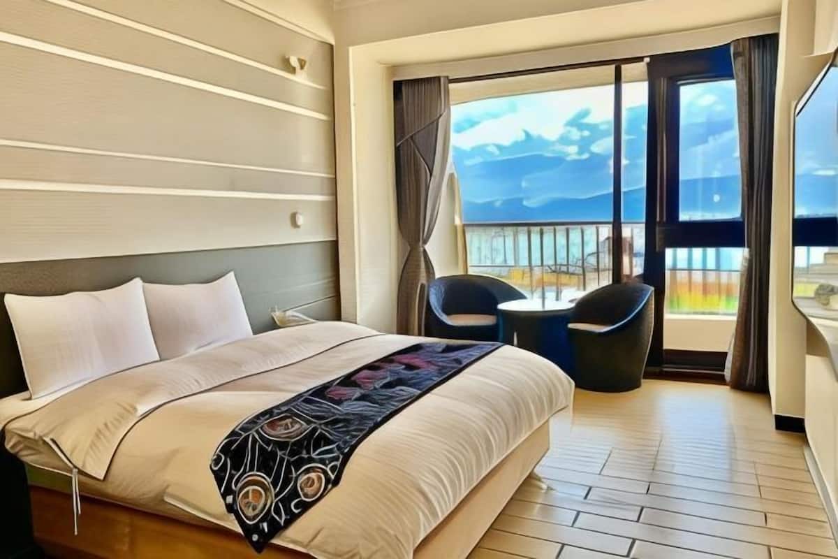 Une chambre d’hôtel avec un lit, une chaise, une table et un balcon offrant une vue.