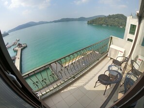 A balcony with a view of a calm lake, a pier with boats, and a mountainous landscape. - Ming Yue Hu Hotel (Yuchi)