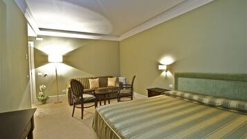 A hotel room with a bed, a desk, a chair, and a lamp.