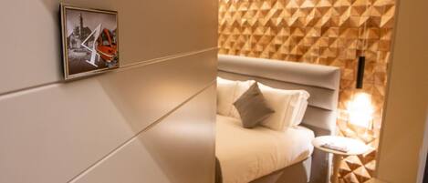 A modern hotel room with a bed, a small bedside table, and a geometric patterned wall.