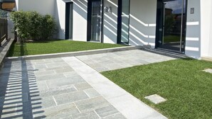 A modern building with a flat roof, large windows, and a stone pathway leading to the entrance.