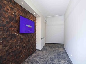 Een gang met een houten wand en een tv met daarop 'Sky Music'.