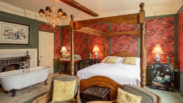 Un dormitorio tradicional con cama con dosel, bañera de patas de león y muebles ornamentados.