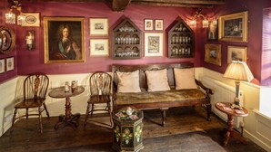 A room with a wooden bench, two chairs, a small table, and a radiator. - Ye Spotted Dogge (Portsmouth)