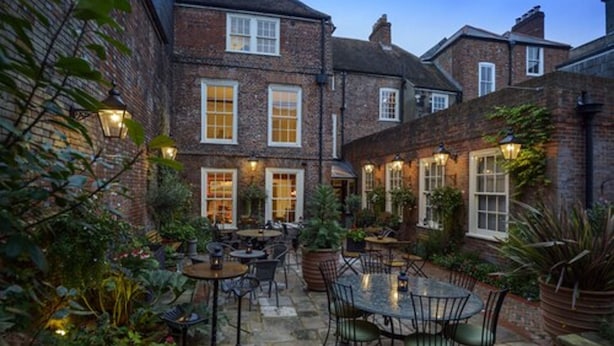 A courtyard with brick buildings, outdoor seating, and potted plants. - Ye Spotted Dogge (Portsmouth)