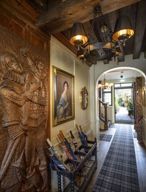 A hallway with a wooden carving, a framed portrait, and a rack of umbrellas. - Ye Spotted Dogge (Portsmouth)