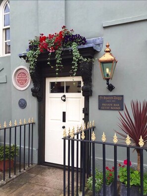 A building entrance with a white door, a sign indicating a private bar and guest rooms, and a decorative lantern. - Ye Spotted Dogge (Portsmouth)