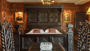 A room with a large bed, ornate headboard, and a chandelier. - Ye Spotted Dogge (Portsmouth)