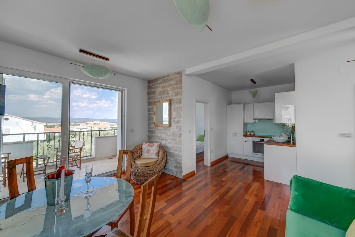 A modern apartment with a dining area, kitchen, and balcony.